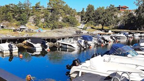 A marina with boats docked, a wooden pier, and a rocky hillside with trees in the background. - 4 Star Holiday Home in Sondeled (Risør)