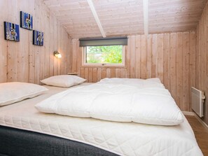 A room with a bed, a window, wooden walls, and a wall-mounted light fixture. - 6 Person Holiday Home in Ansager (Ansager)