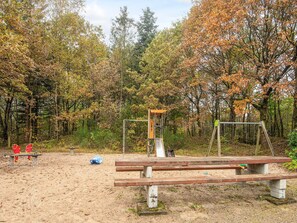 A playground with a slide and swings, surrounded by trees with autumn foliage. - 6 Person Holiday Home in Ansager (Ansager)