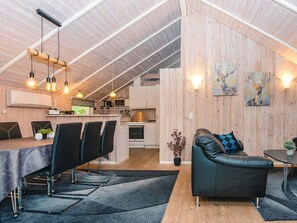 A modern kitchen with a dining area, featuring a wooden ceiling, pendant lighting, and a sofa with a geometric pillow. - 6 Person Holiday Home in Ansager (Ansager)
