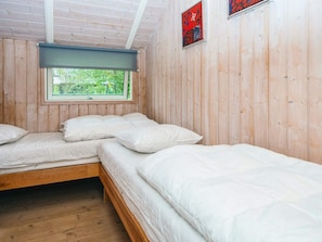A room with three beds, wooden walls, a window with a view of greenery, and a red artwork on the wall. - 6 Person Holiday Home in Ansager (Ansager)