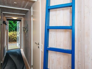 A narrow hallway with a wooden door on the right and a window on the left.