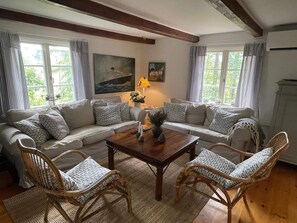 A cozy living room with a sofa set, two wicker chairs, a wooden coffee table, and a painting on the wall.