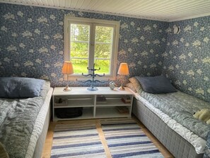 A cozy room with two beds, a window, and a small table with lamps. - 8 Person Holiday Home in Hallabro (Hallaröd)