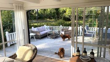 Um deck coberto com móveis de exterior, um cão e garrafas de vinho.