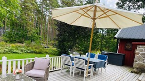 Eine Terrasse mit Korbmöbeln, einem Tisch mit einer Vase und einem großen Sonnenschirm.