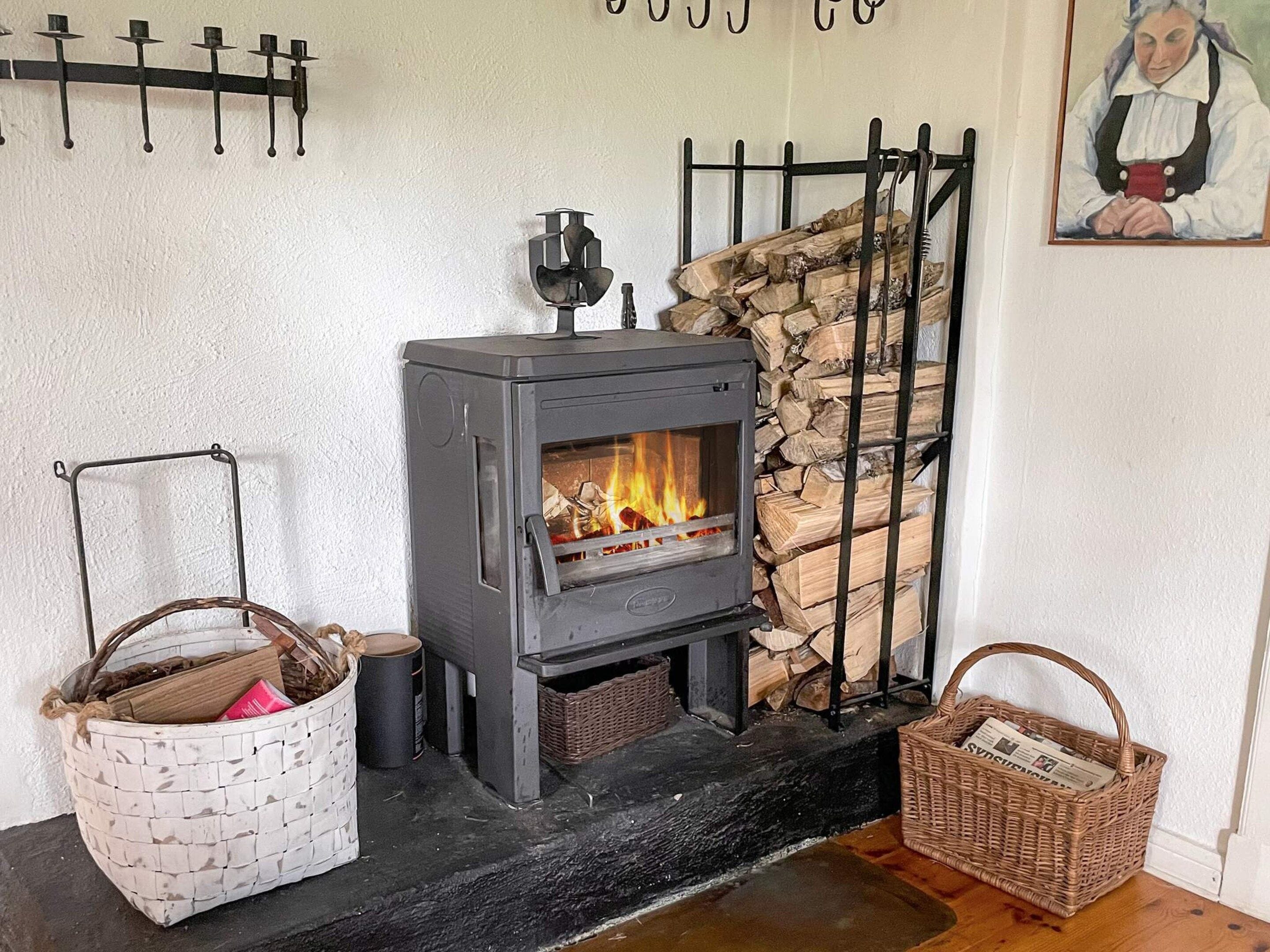 A wood-burning stove with logs, a basket, and a wicker basket on the floor.