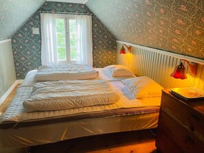 Ein Schlafzimmer mit einem großen Bett, einem Schminktisch und einem Fenster mit Vorhängen.