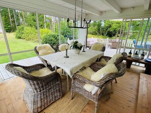 An outdoor patio with wicker furniture, a table with a white tablecloth, and a chandelier. - 8 Person Holiday Home in Hallabro (Hallaröd)