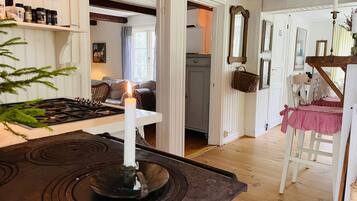 A kitchen with a stove, a lit candle, and a dining area with a table and chairs.