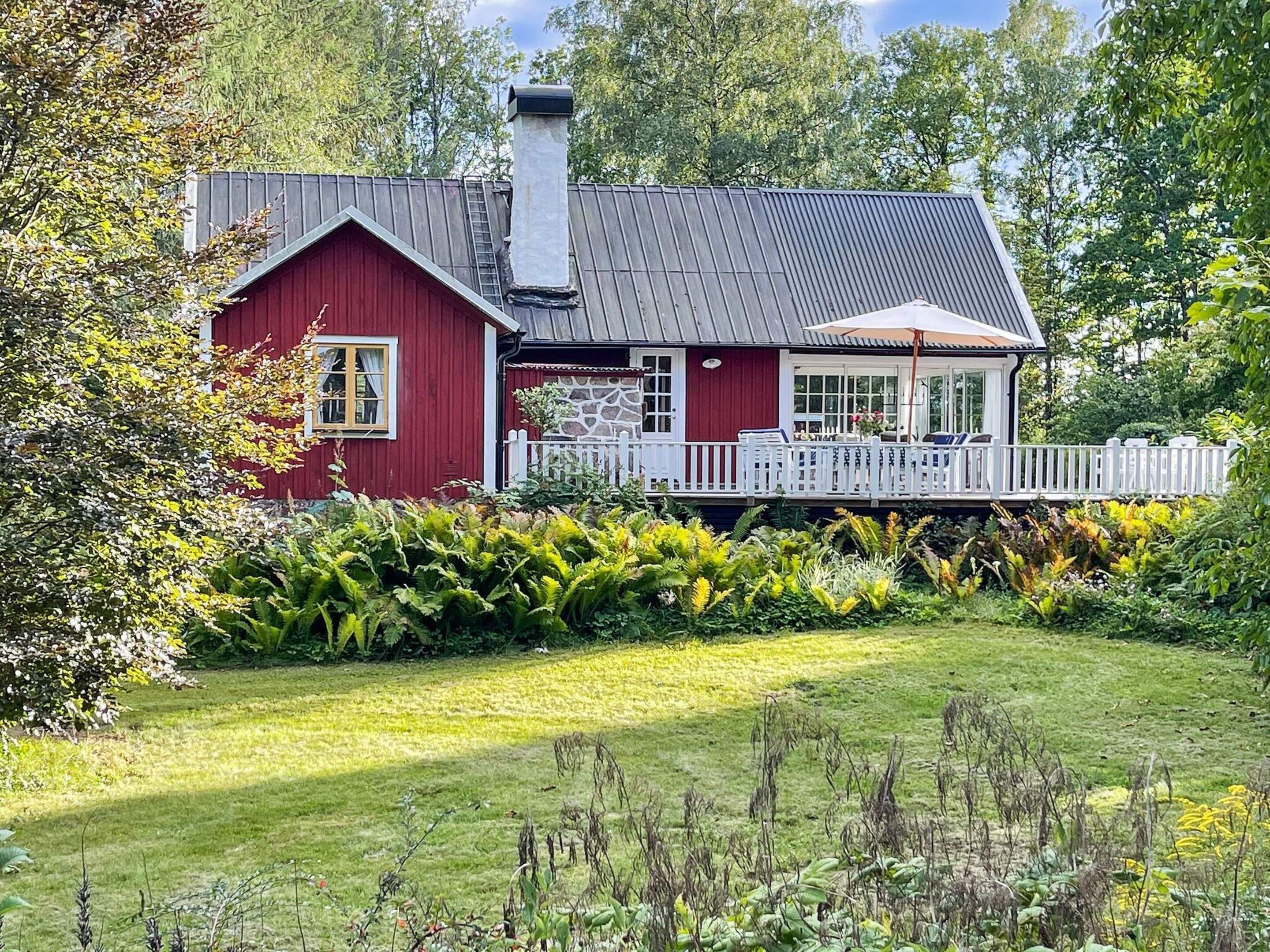 A red house with a stone facade, a white picket fence, and a grassy yard.