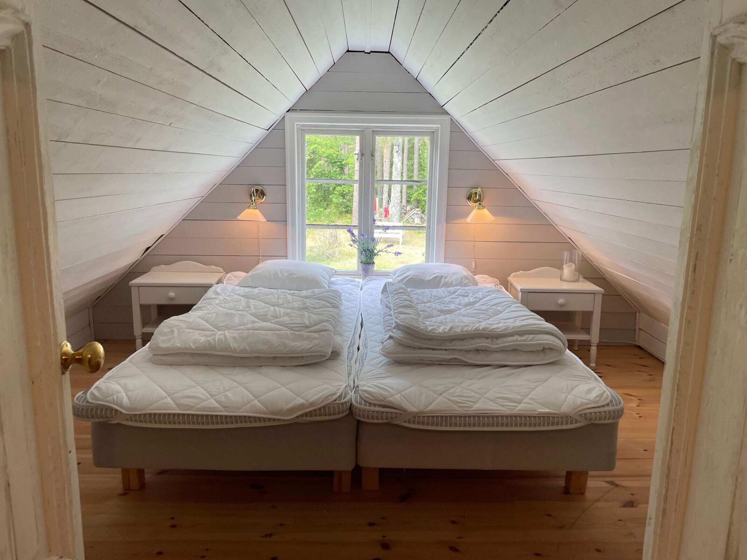 A bedroom with two beds, a window, and bedside lamps.