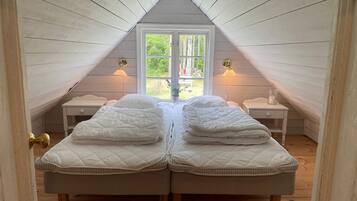 A bedroom with two beds, a window, and bedside lamps.