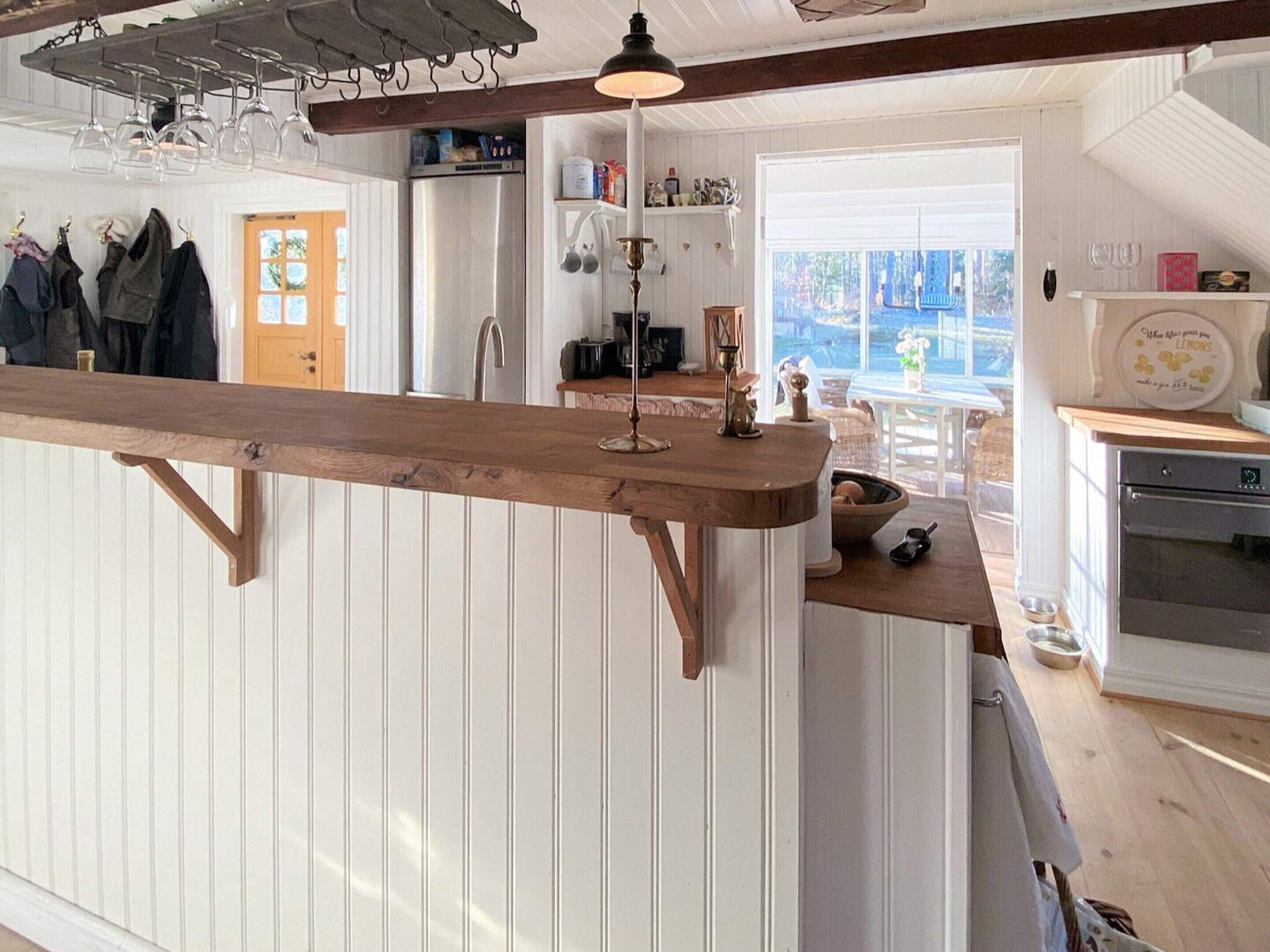 A kitchen with a wooden bar counter, a refrigerator, and a dining area with a view.