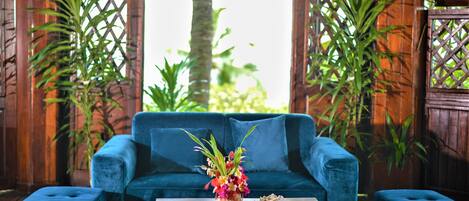 A blue sofa with a wooden coffee table in front, surrounded by wooden lattice panels and potted plants.