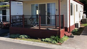 A mobile home with a porch, a covered patio, and a fenced outdoor area.