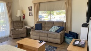 A living room with a sofa, armchair, coffee table, and TV.