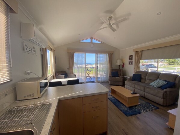A compact living space with a kitchenette, a dining area, a sofa, and a view of the outdoors.