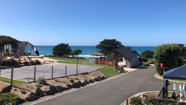 A coastal resort with a playground, a gazebo, and a clear view of the sea.