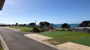A coastal road with a grassy area and a playground.