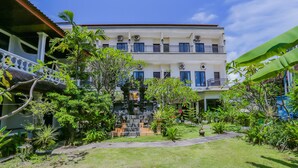 Un edificio de dos plantas con un balcón en el piso superior y un jardín cuidado en la parte delantera.