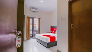 Habitación de hotel con cama, puerta de madera, puerta corredera de vidrio y un cartel con la inscripción 'DND'.