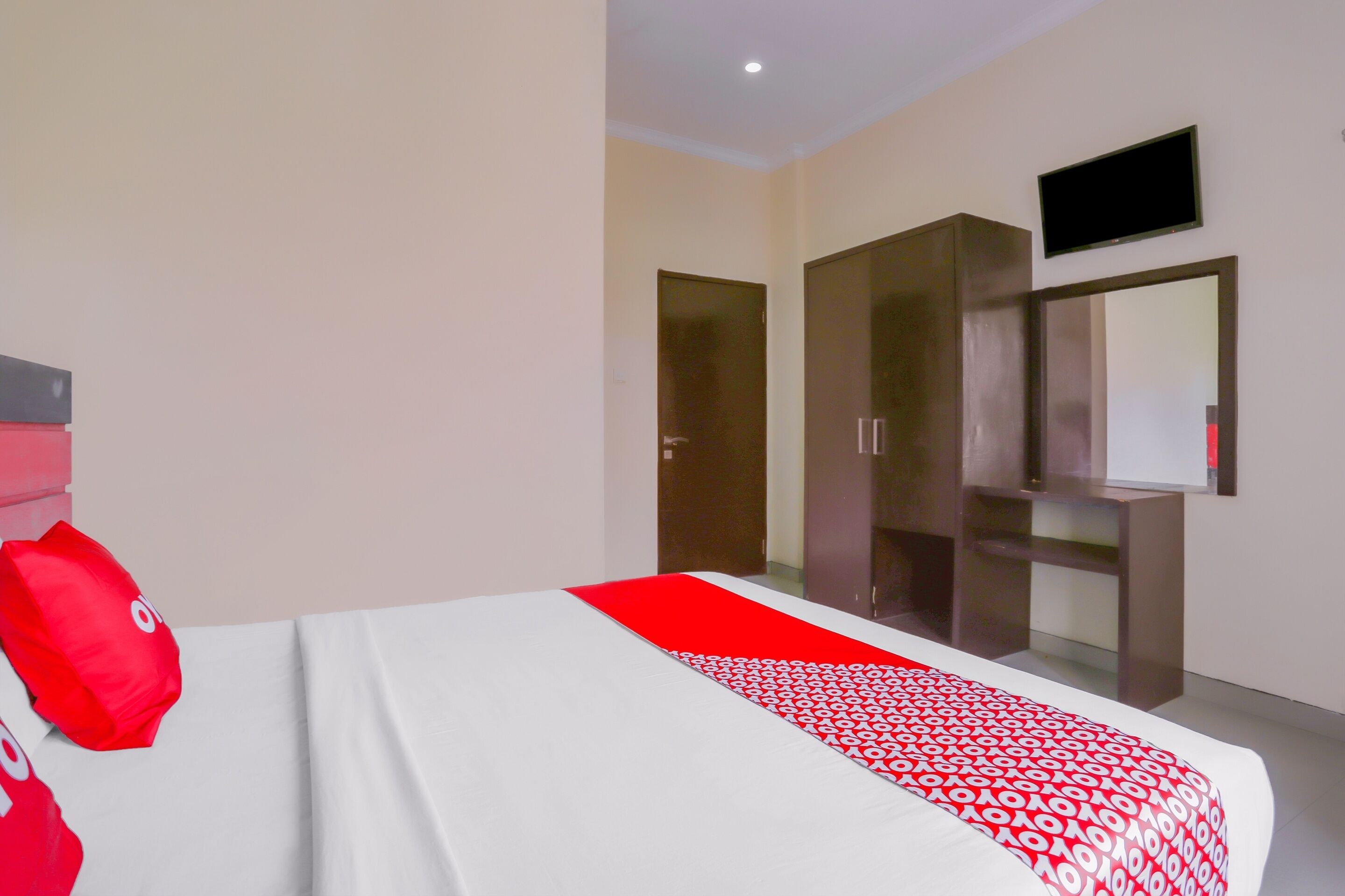 A hotel room with a bed, a wardrobe, a television, and a door.