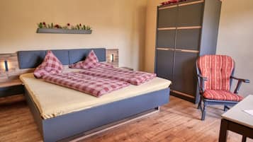 Un dormitorio con cama, una silla, un armario y una estantería con plantas.