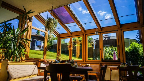 Una habitación iluminada por el sol con un tragaluz grande, muebles de madera y plantas en macetas.