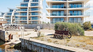 A modern multi-story building with balconies and large windows, located near a dock with a wooden walkway. - 5 Star Holiday Home in Wendtorf (Wendtorf)