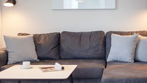 A modern living room with a sectional sofa, a small white table, and a magazine.