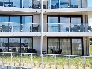 A multi-story building with balconies, large windows, and outdoor seating areas.