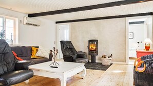 Una sala de estar con chimenea, sofás de cuero, una mesa de centro blanca y una silla de mimbre.