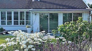 Ein Haus mit Ziegeldach, großen Fenstern und einer Veranda.