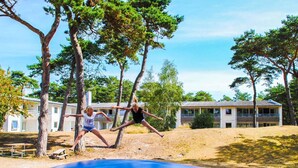 A playground with a slide and trees, and a building in the background. - 2 Person Holiday Home in Nexo (Nexø)