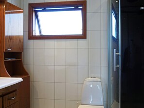 Un baño con inodoro, un armario de madera y una ventana.