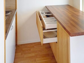 A kitchen with a wooden countertop and a white drawer unit with plates and utensils. - 4 Person Holiday Home in Lysekil (Lysekil)