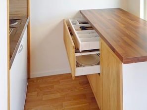 A kitchen with a wooden countertop and a drawer containing plates and utensils. - 4 Person Holiday Home in Lysekil (Lysekil)