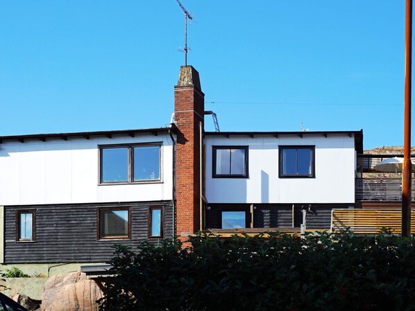 Una casa moderna de dos pisos con chimenea de ladrillo, ventanas amplias y techo plano.