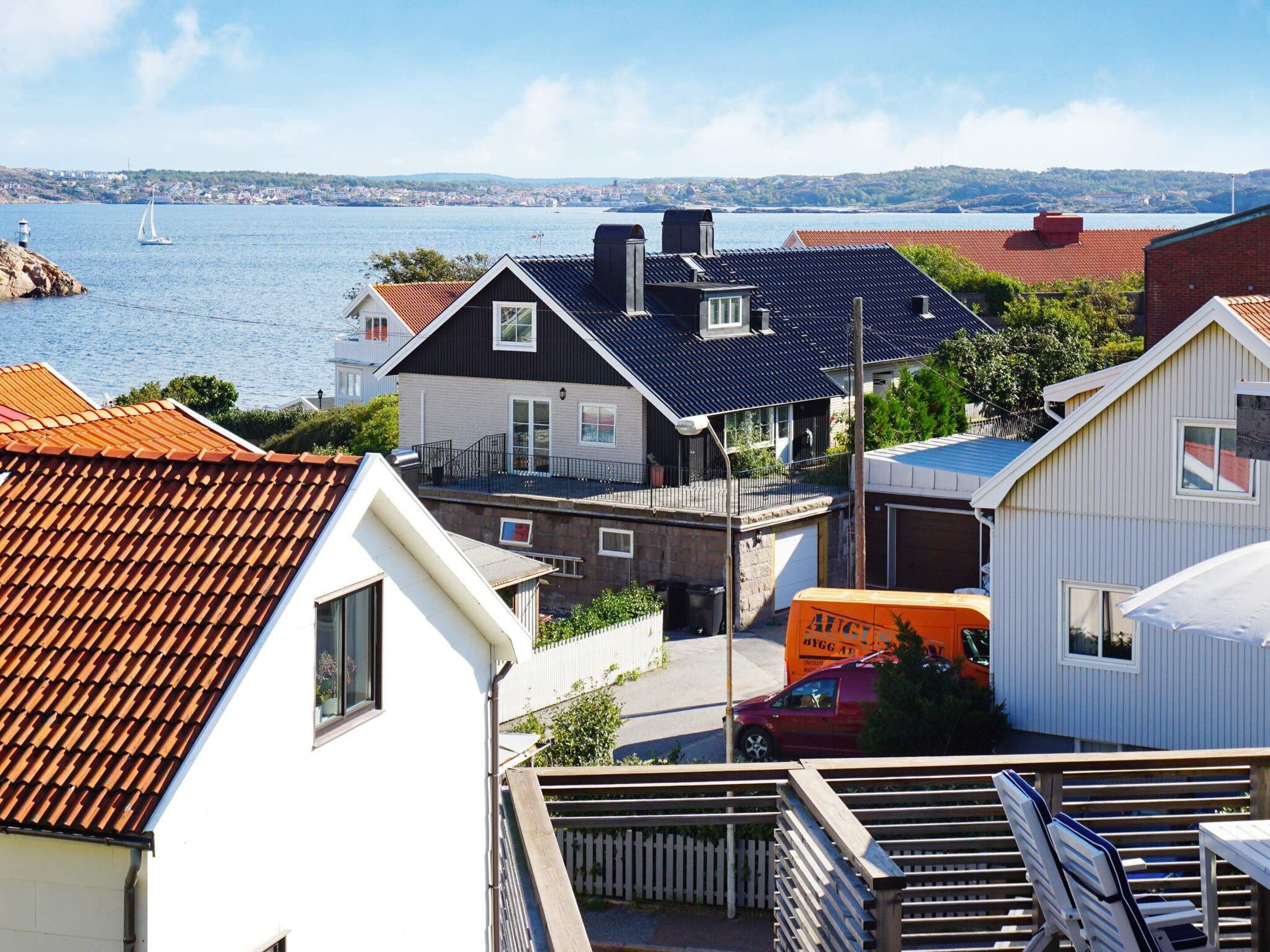 A coastal residential area with houses, a red van, and a sailboat on the water.