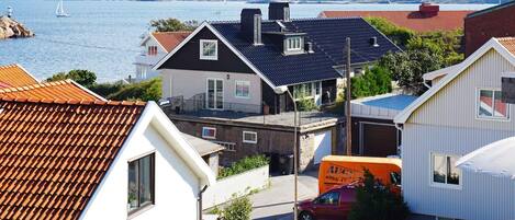 A coastal residential area with houses, a red van, and a sailboat on the water.