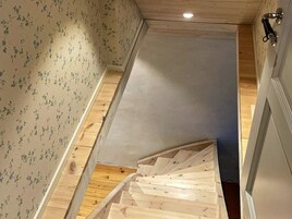 A narrow staircase with wooden steps leading to a landing.