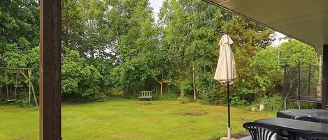 A covered outdoor area with a wooden deck, a bench, and a table with chairs.