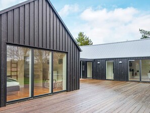 En modern byggnad med stora fönster och en träaltan.