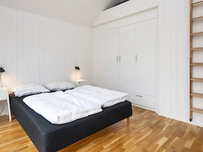 Un dormitorio con cama, mesitas de noche, lámpara y armario.