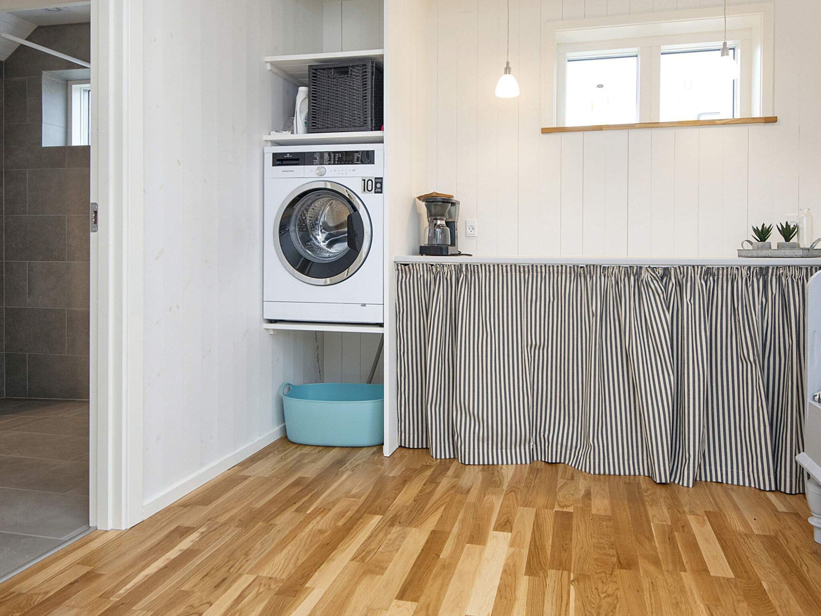 A laundry area with a washing machine, a drying rack, and a blue laundry basket.