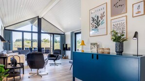 A modern living room with a blue cabinet, a sofa, and a dining area with a table and chairs. - 5 Star Holiday Home in Hirtshals (Hirtshals)