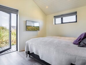A bedroom with a bed, a window, and a view of a landscape. - 5 Star Holiday Home in Hirtshals (Hirtshals)