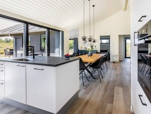 A modern kitchen with a large island, dining area, and a view of the outdoors.