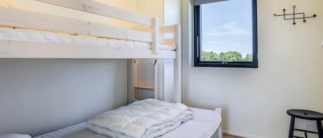 Ein Stockbett mit einer unteren Liege, ein Fenster mit Blick und ein kleiner Hocker.